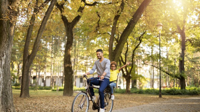 father and daughter riding bike through the park